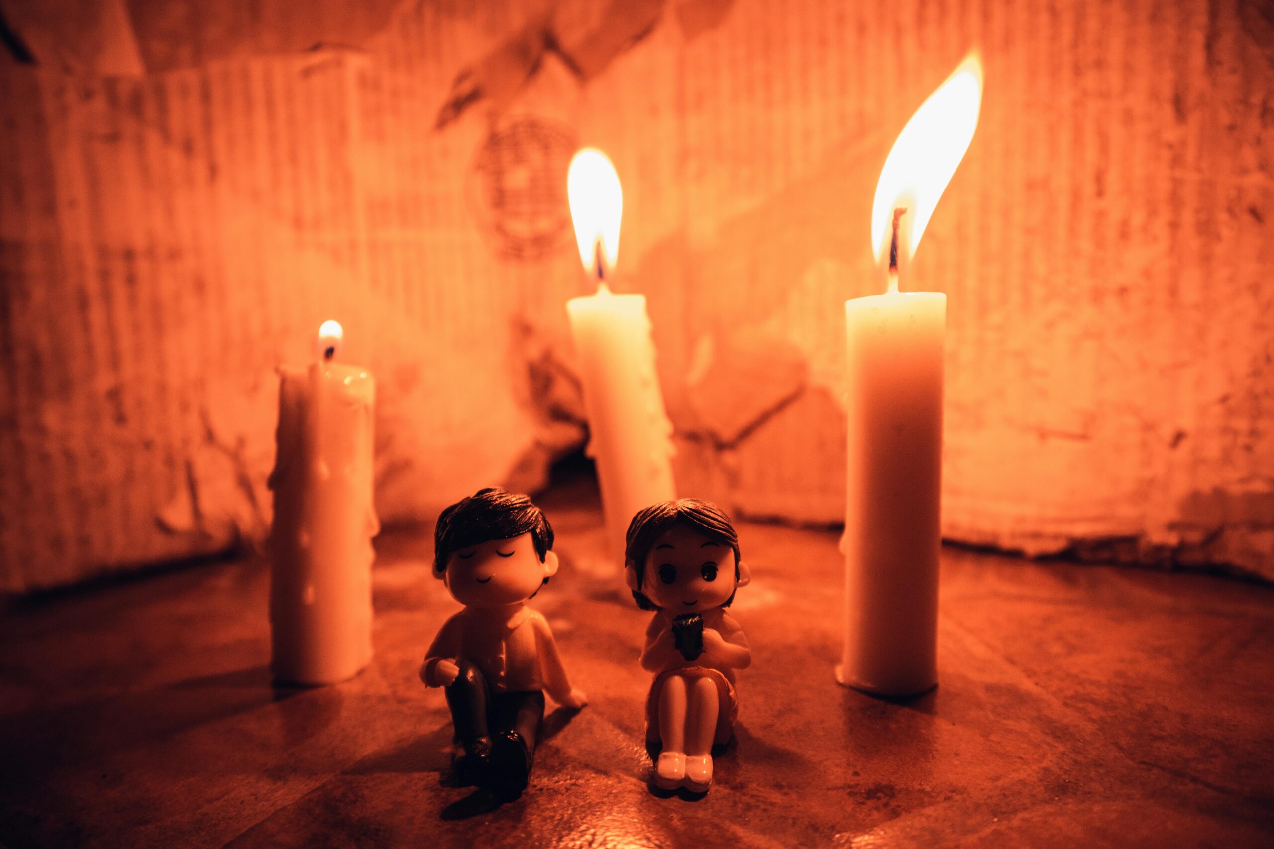 Two cute figurines lit by candlelight create a romantic, warm ambiance.